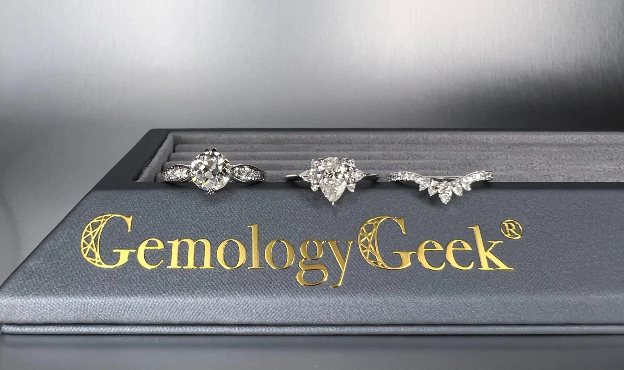 Custom natural diamond engagement rings by GemologyGeek® displayed on a branded jewelry presentation box.