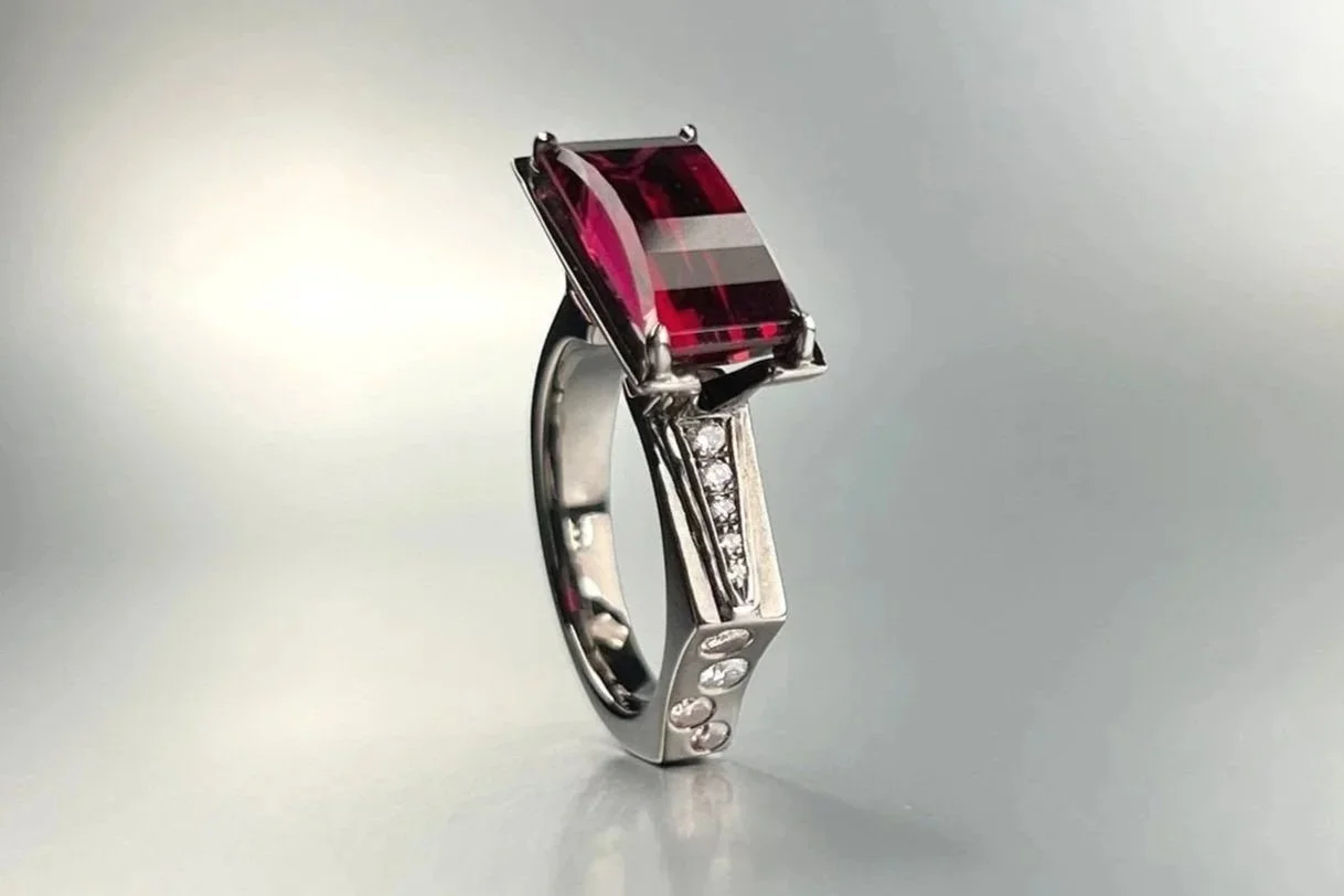 Three-quarter view of a custom 14k white gold ring featuring a 4.17 ct red tourmaline with natural white diamonds and Argyle pink diamond accents.