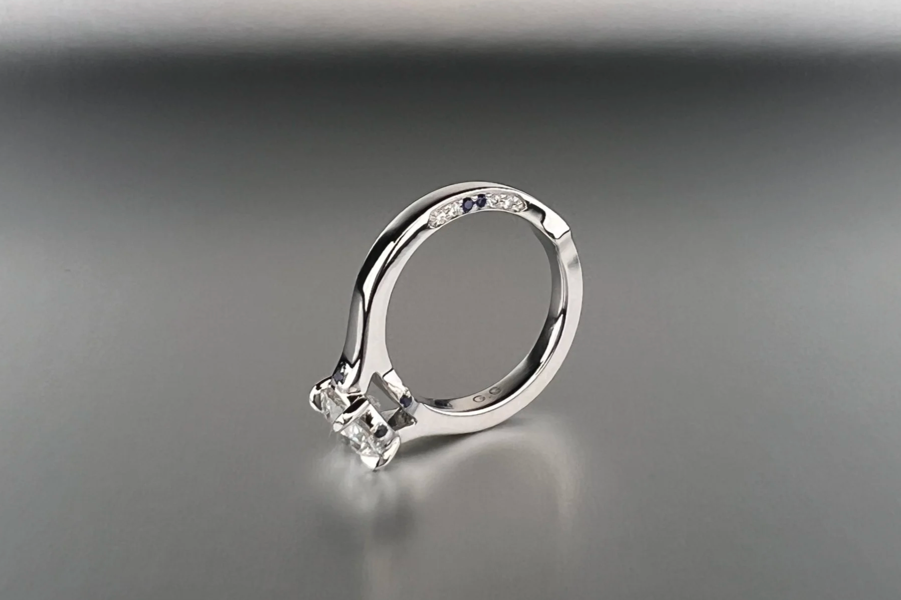 Custom platinum engagement ring featuring a 1.35 ct Old European cut natural diamond with pavé natural diamonds and blue sapphire accents.