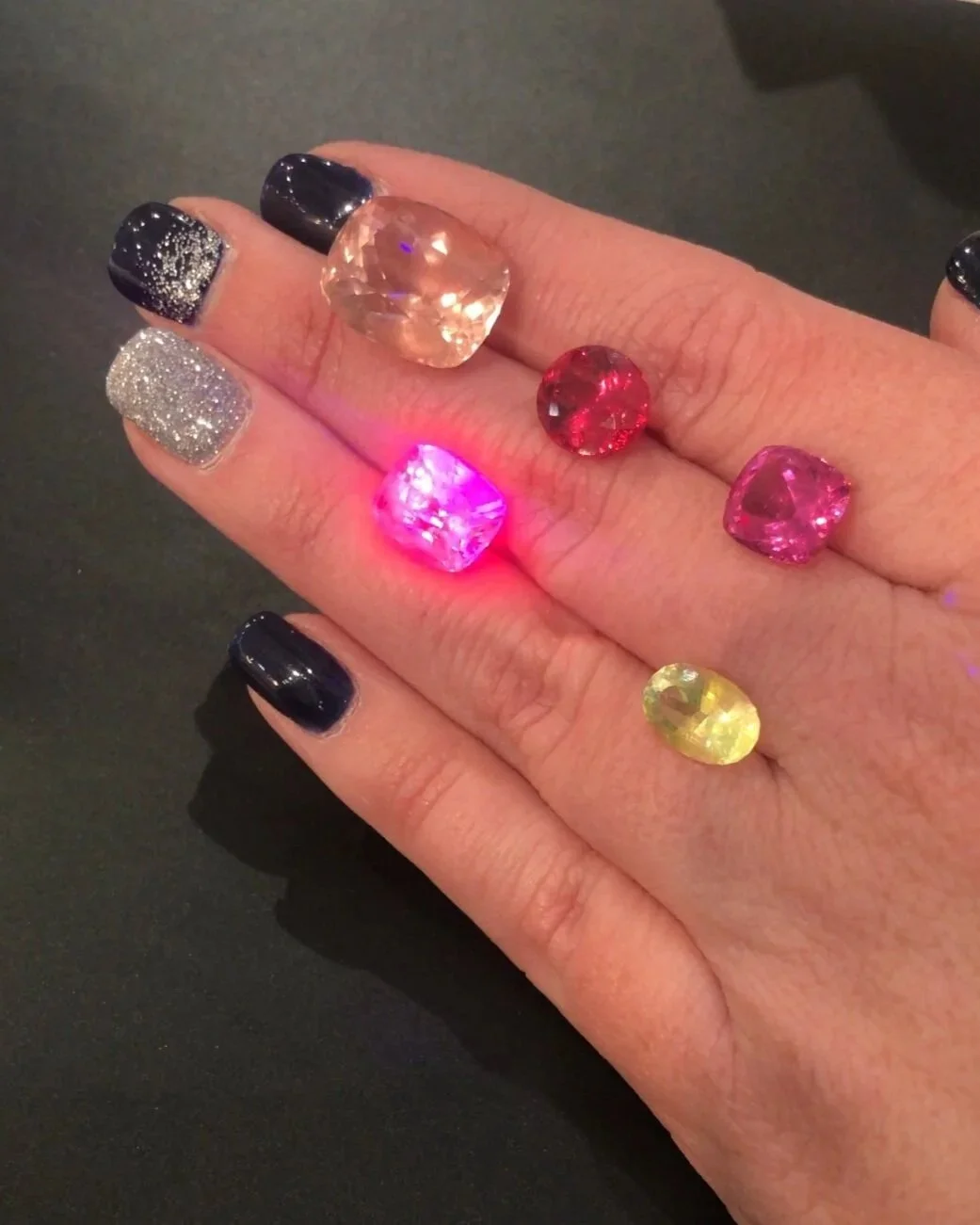 Natural gemstones displaying fluorescence under ultraviolet light during gemological examination.