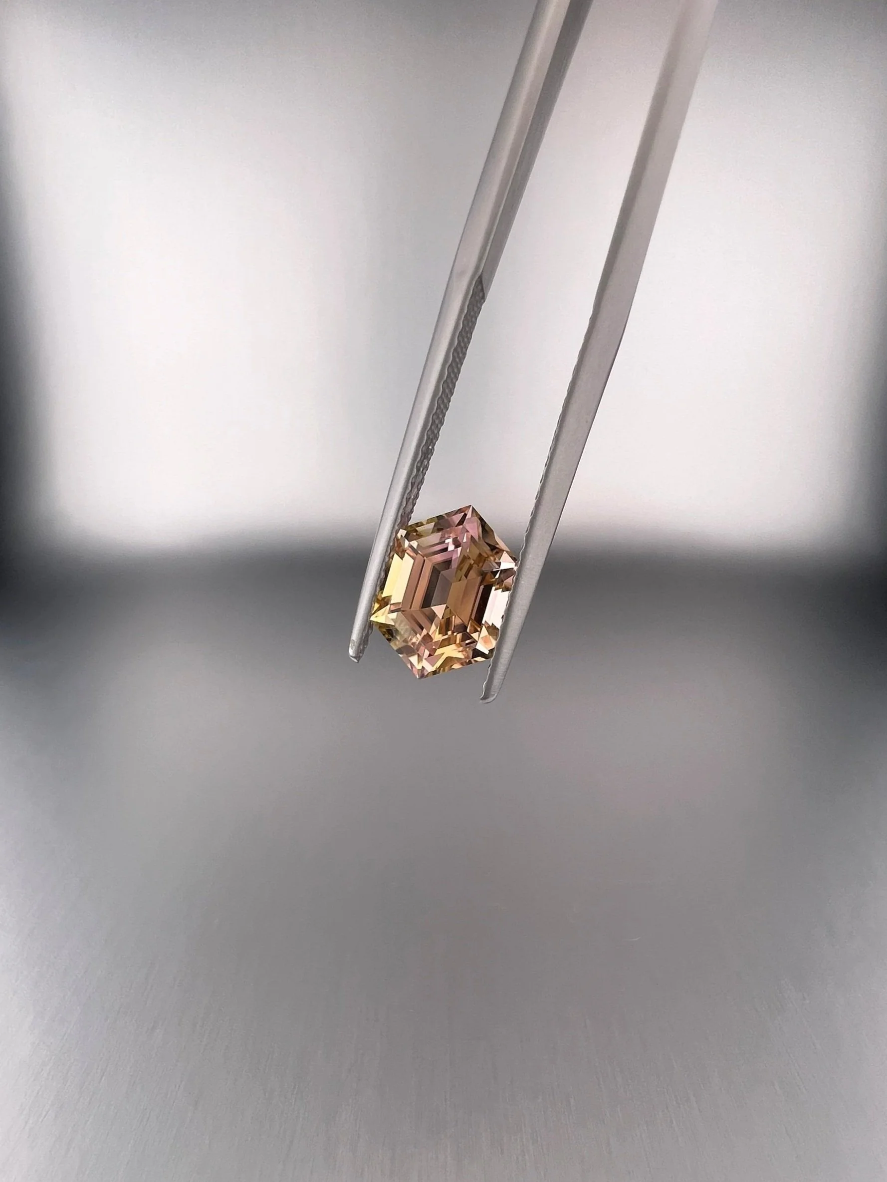 A 2.06 carat bi-color peach tourmaline with a hexagon cut, displaying stunning peach hues and exceptional clarity, highlighting its unique and elegant gem quality.