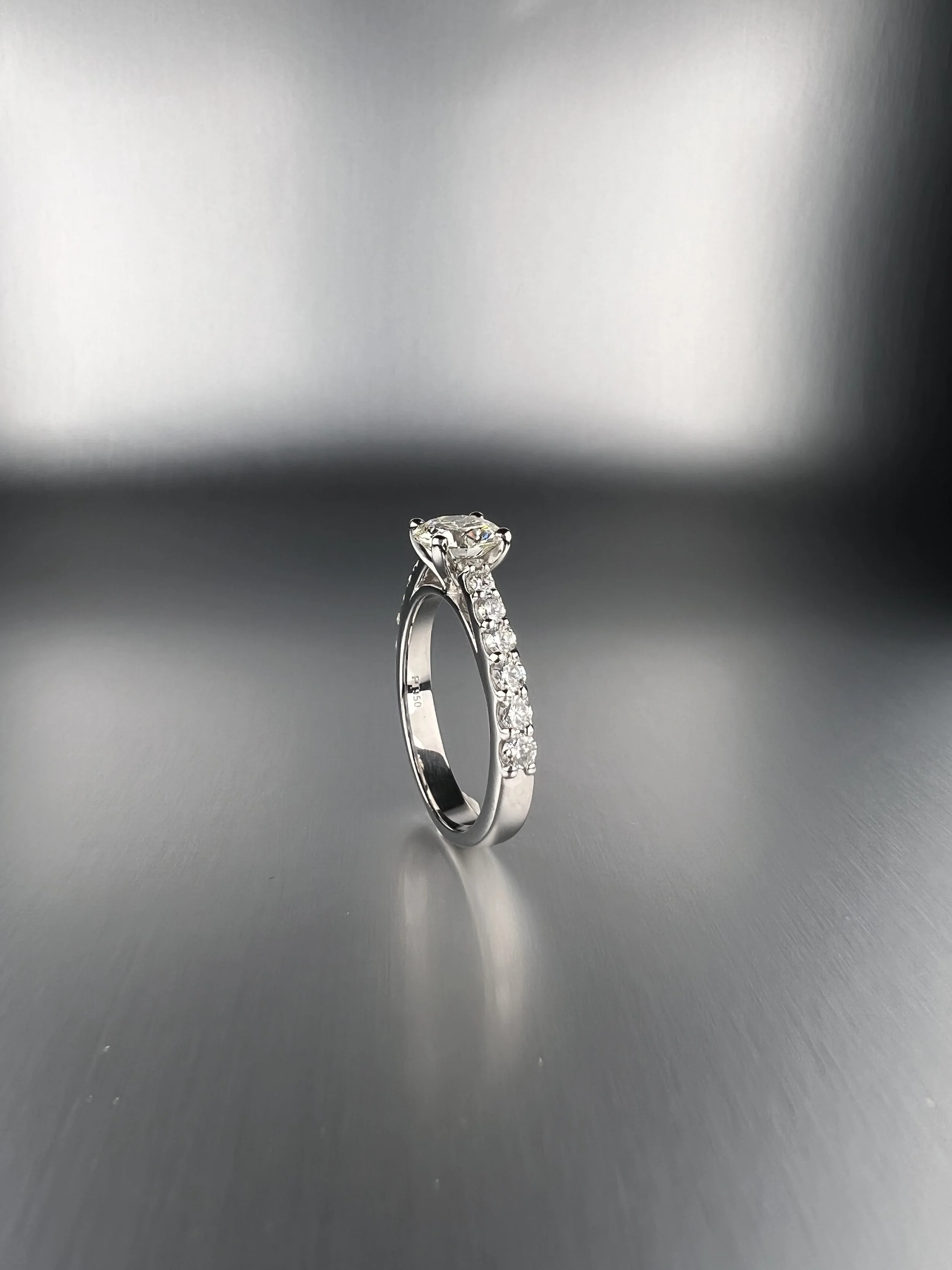 Side view of a custom platinum engagement ring featuring a 1.00 ct round brilliant natural diamond with pavé natural diamond accents.