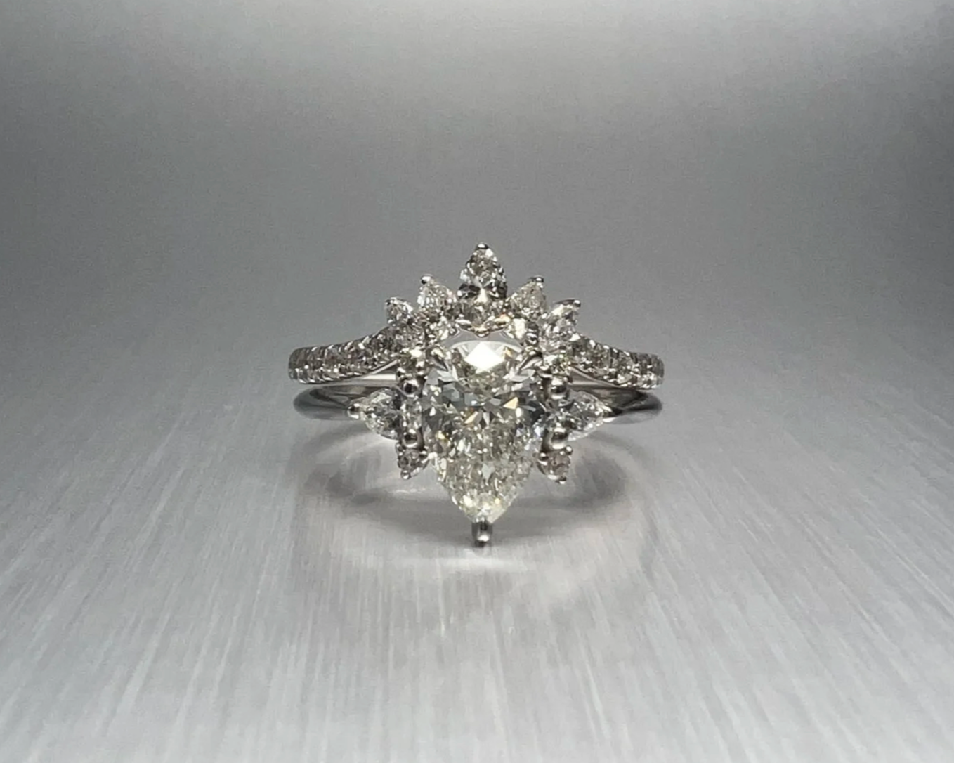 Top view of a custom platinum engagement ring featuring a 1.00 ct pear-shaped natural diamond with pear, marquise, and round natural diamond accents.