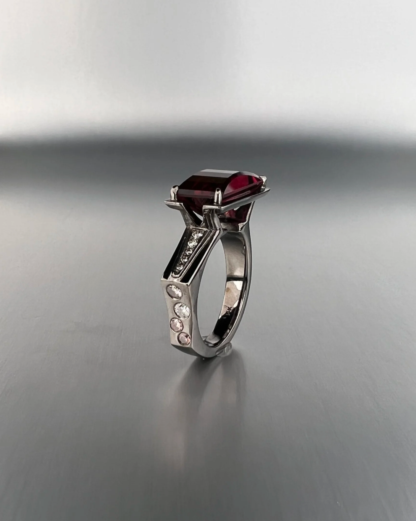 Side view of a custom 14k white gold ring featuring a 4.17 ct red tourmaline with natural white diamonds and Argyle pink diamond accents.