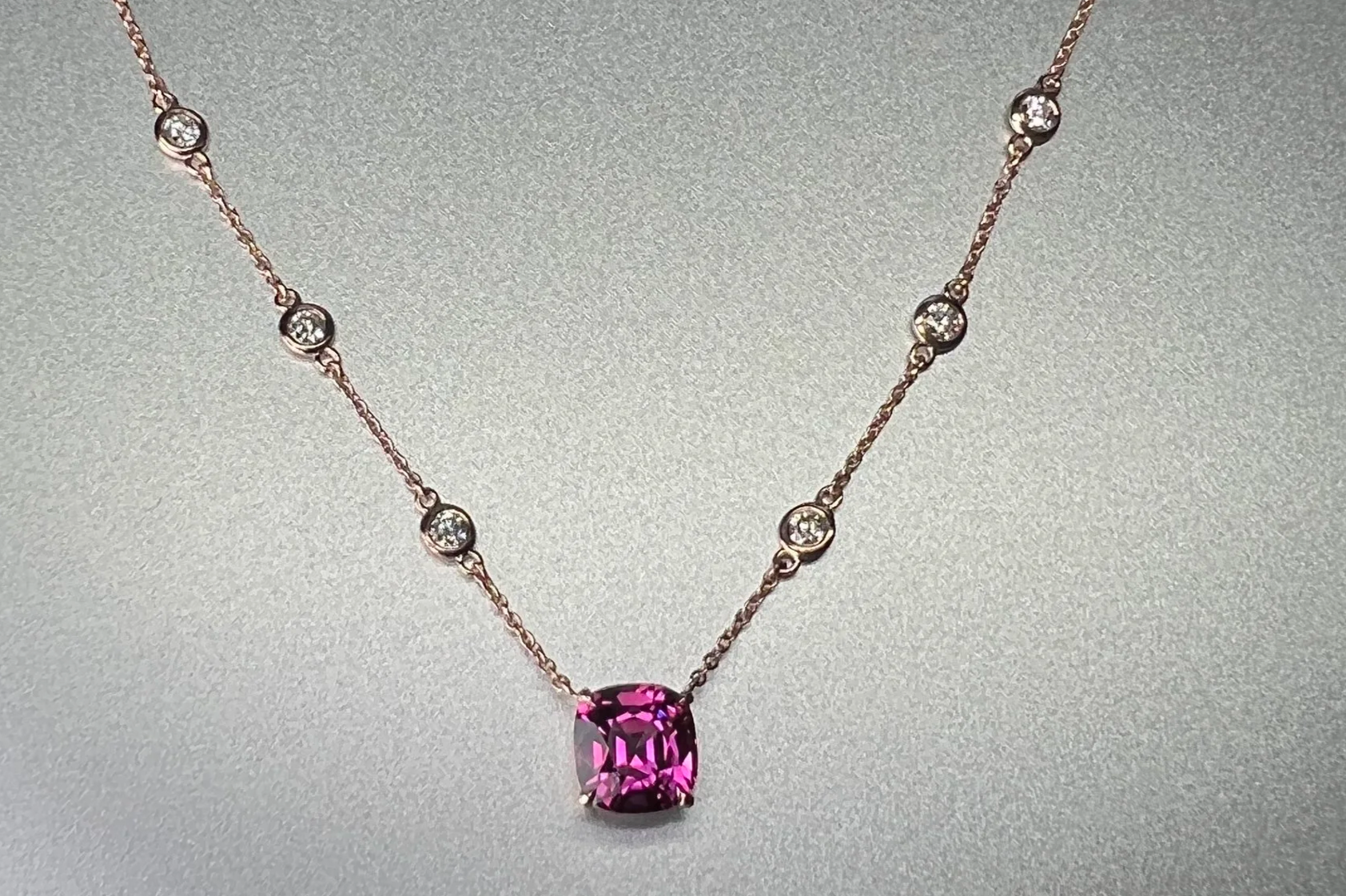Front view of a custom 14k rose gold station necklace featuring a 2.28 ct Umbalite garnet with bezel-set natural diamond stations.