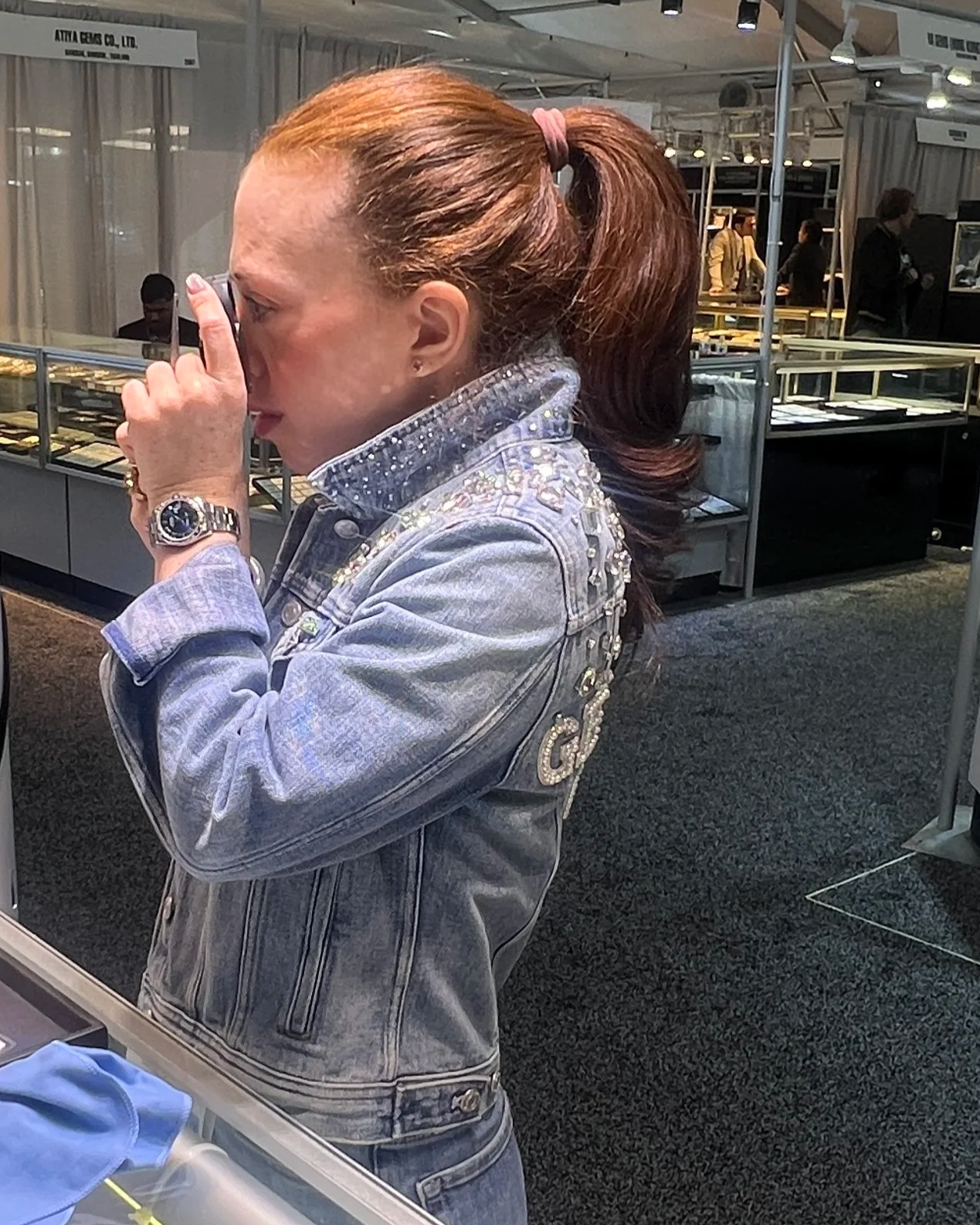 Erica Silverglide examining a natural gemstone with a jeweler's loupe during a gem evaluation.
