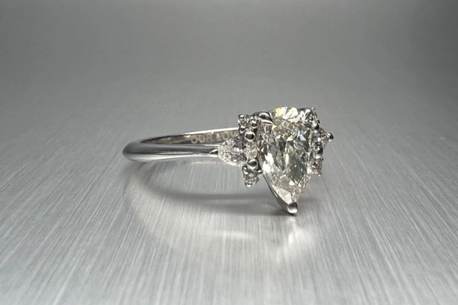Custom platinum engagement ring featuring a 1.00 ct pear-shaped natural diamond with pear, marquise, and round natural diamond accents.