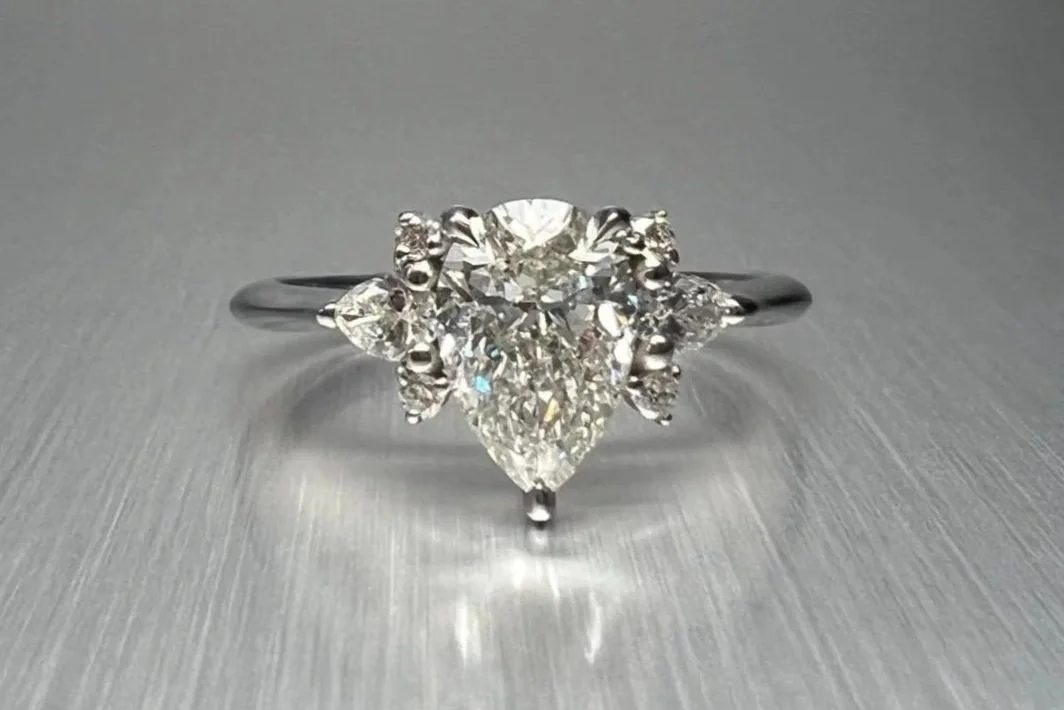 Front view of a custom platinum engagement ring featuring a 1.00 ct pear-shaped natural diamond with pear, marquise, and round natural diamond accents.