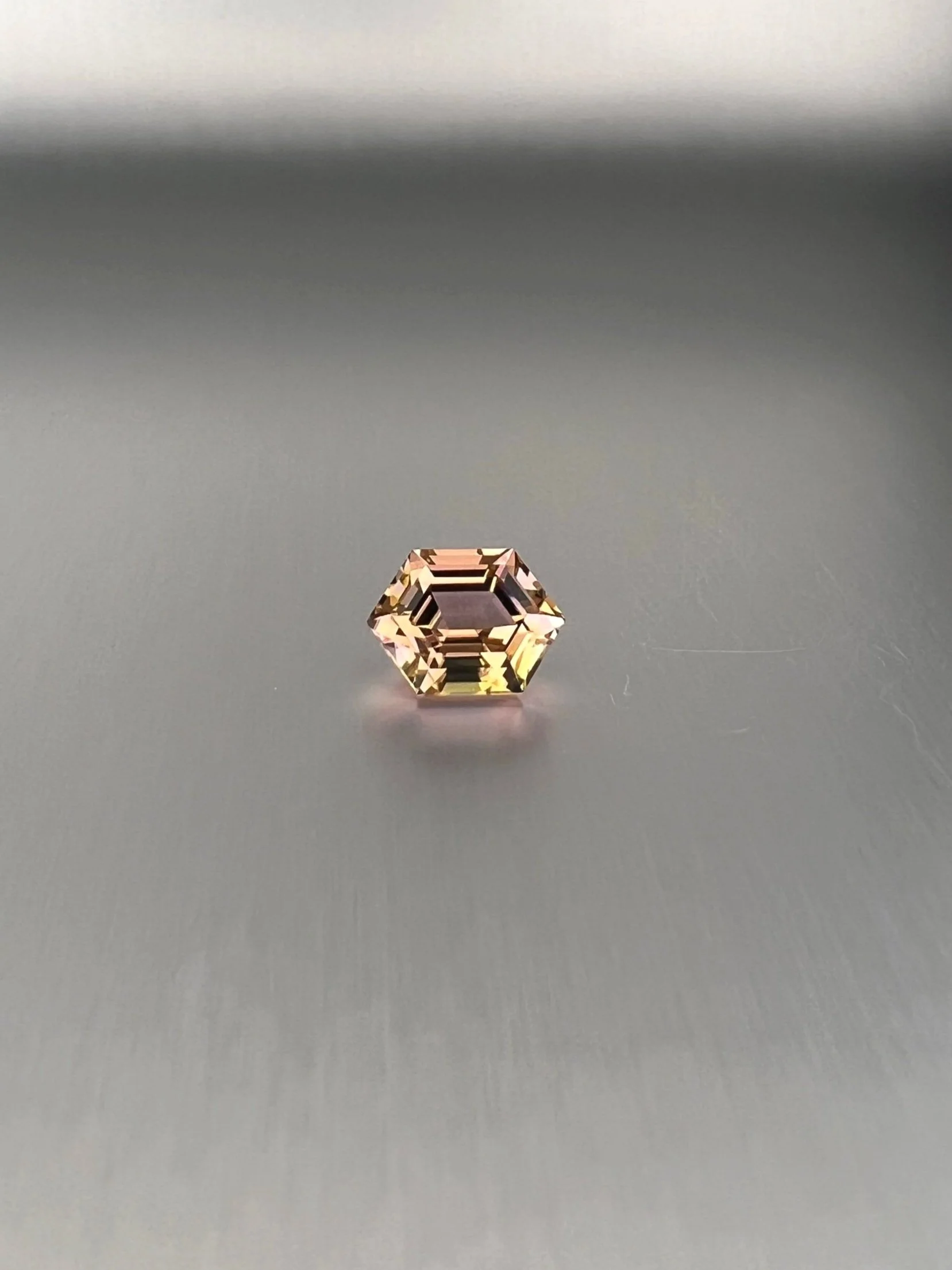 A 2.06 carat bi-color peach tourmaline with a hexagon cut, displaying stunning peach hues and exceptional clarity, highlighting its unique and elegant gem quality.