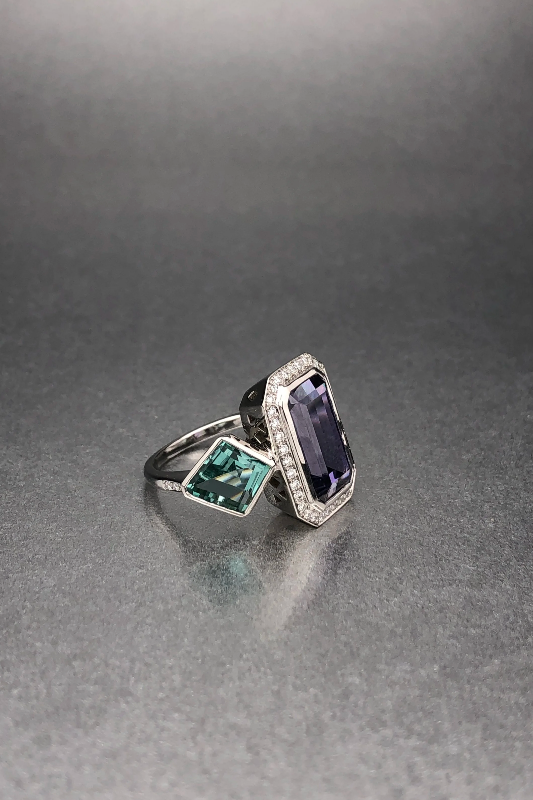 Custom platinum ring featuring a 4.67 ct emerald-cut tanzanite, matched no-heat kite-shaped lagoon tourmalines, and a natural diamond pavé halo.