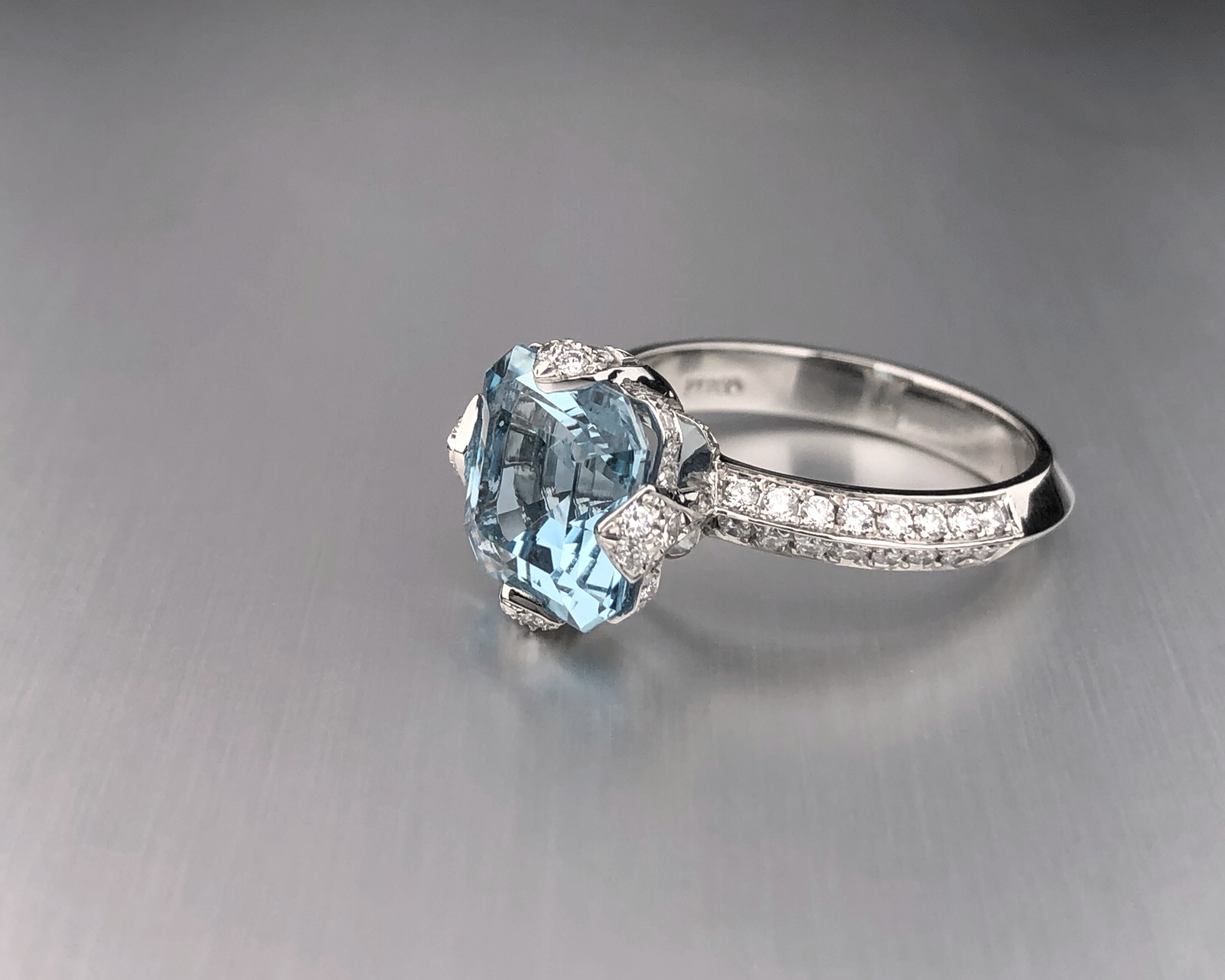 Side view of a custom platinum engagement ring featuring a 2.46 ct Asscher-cut aquamarine with natural diamond accents.