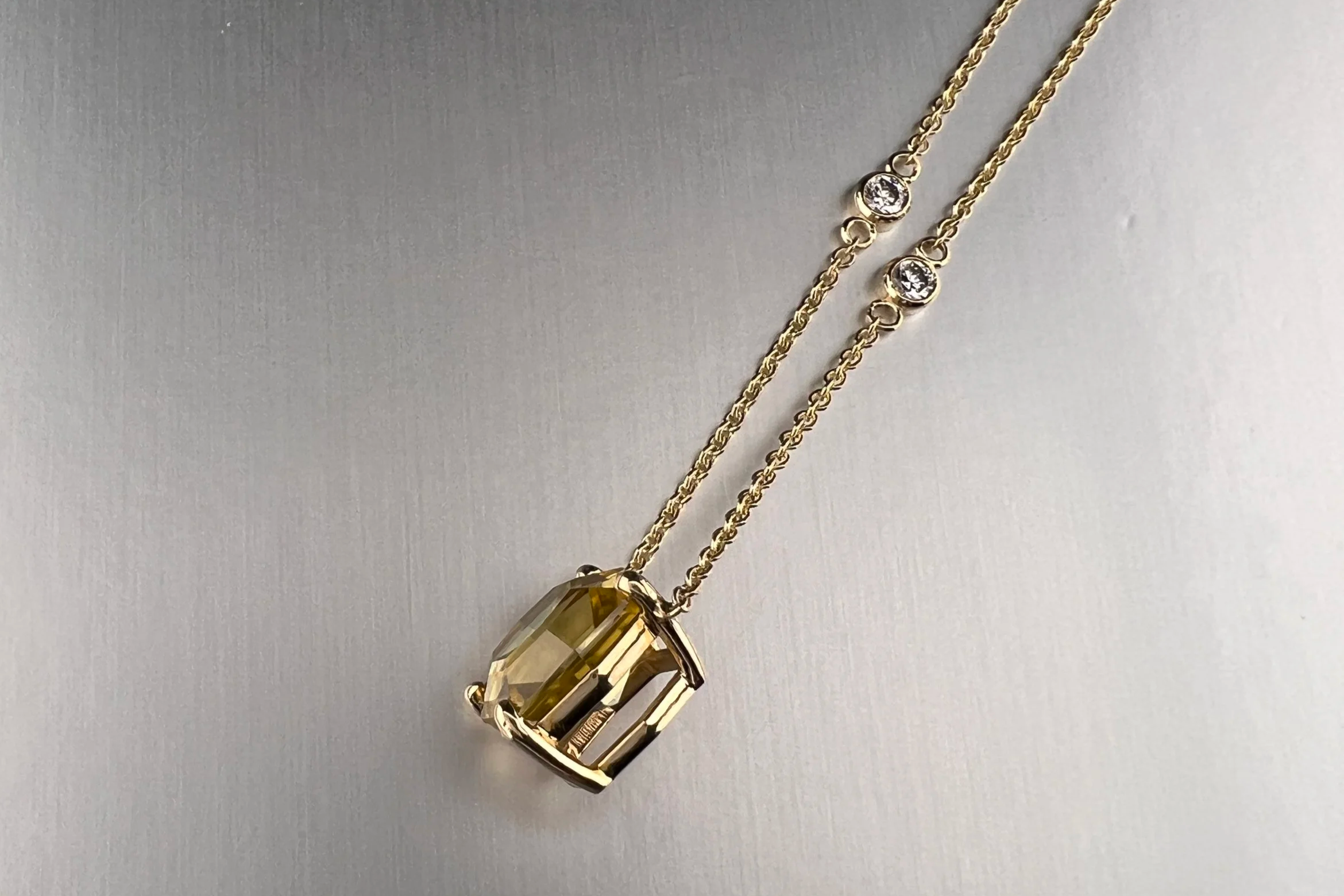 Angled view of a custom 18k yellow gold station necklace featuring a 5.01 ct golden zircon with bezel-set natural diamond stations.