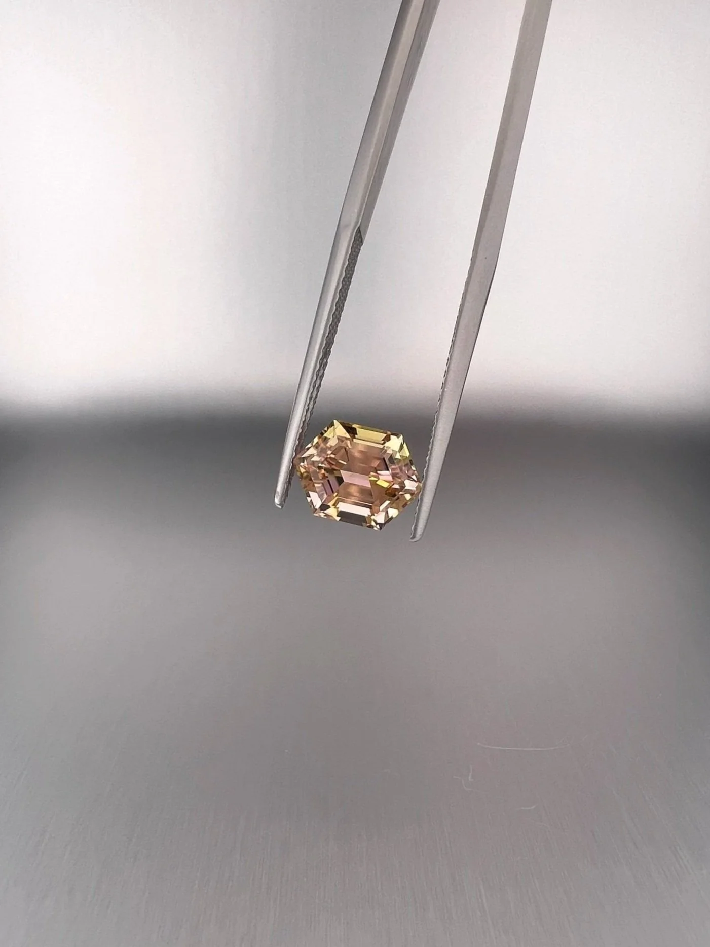 A 2.06 carat bi-color peach tourmaline with a hexagon cut, displaying stunning peach hues and exceptional clarity, highlighting its unique and elegant gem quality.