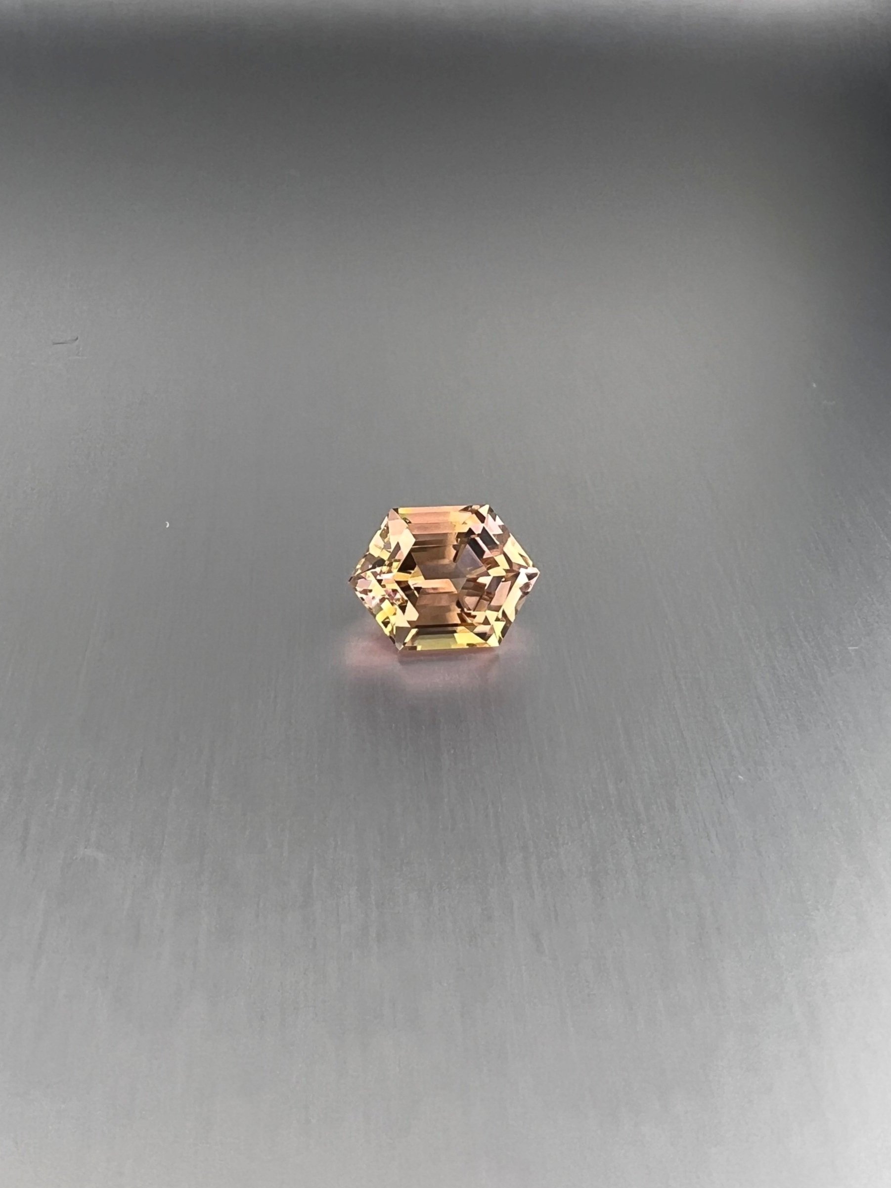 A 2.06 carat bi-color peach tourmaline with a hexagon cut, displaying stunning peach hues and exceptional clarity, highlighting its unique and elegant gem quality.