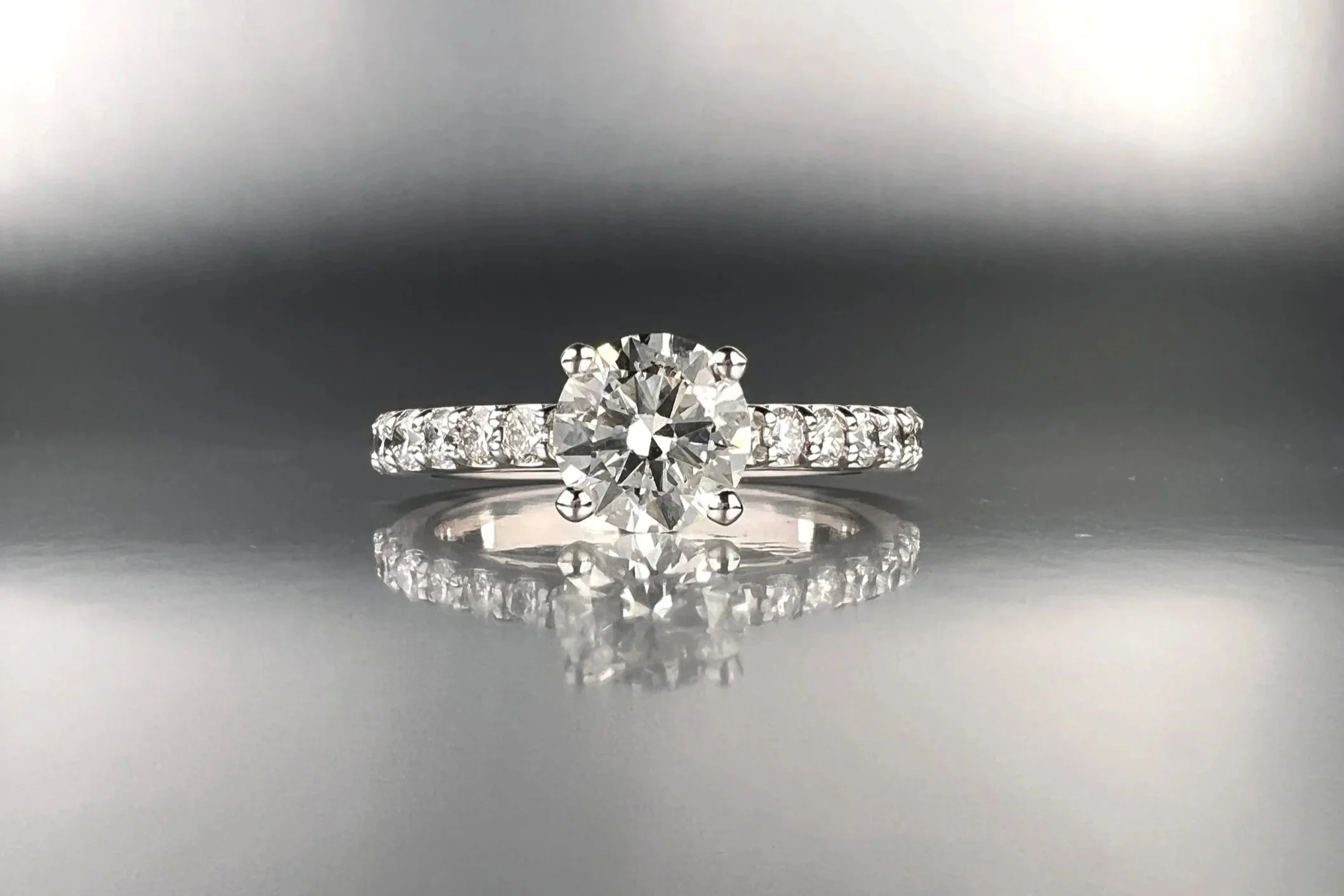 Front view of a custom platinum engagement ring featuring a 1.00 ct round brilliant natural diamond with pavé natural diamond accents.