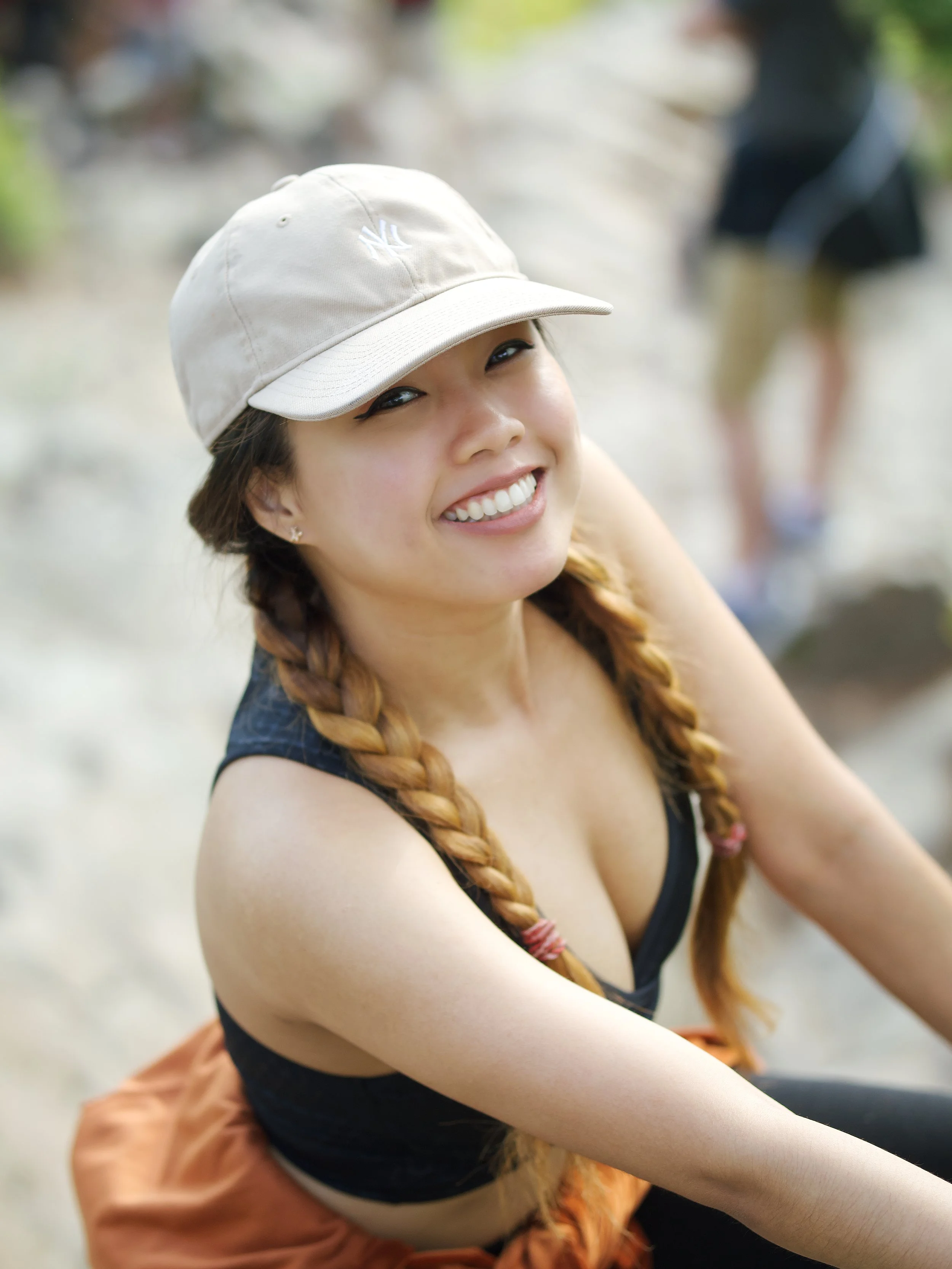Smiling young woman wearing a baseball cap during an outdoor hiking lifestyle portrait session in NYC.