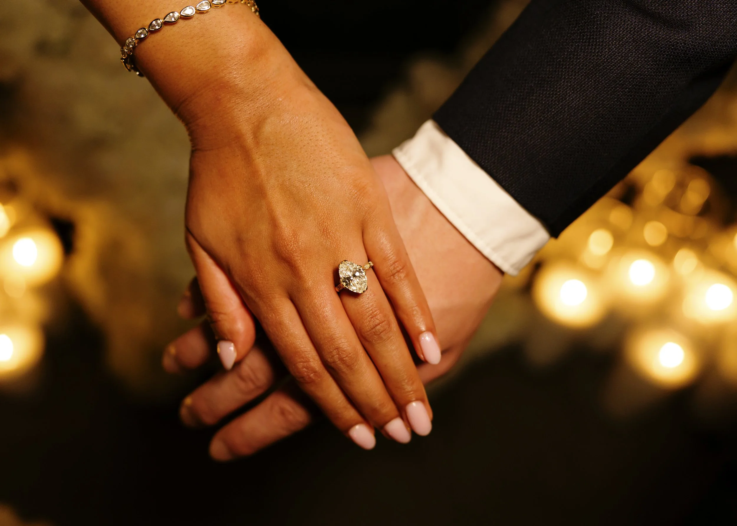 Close-up of bride's engagement ring resting on groom's hand, captured by New York  wedding photographer at outdoor proposal shoot.