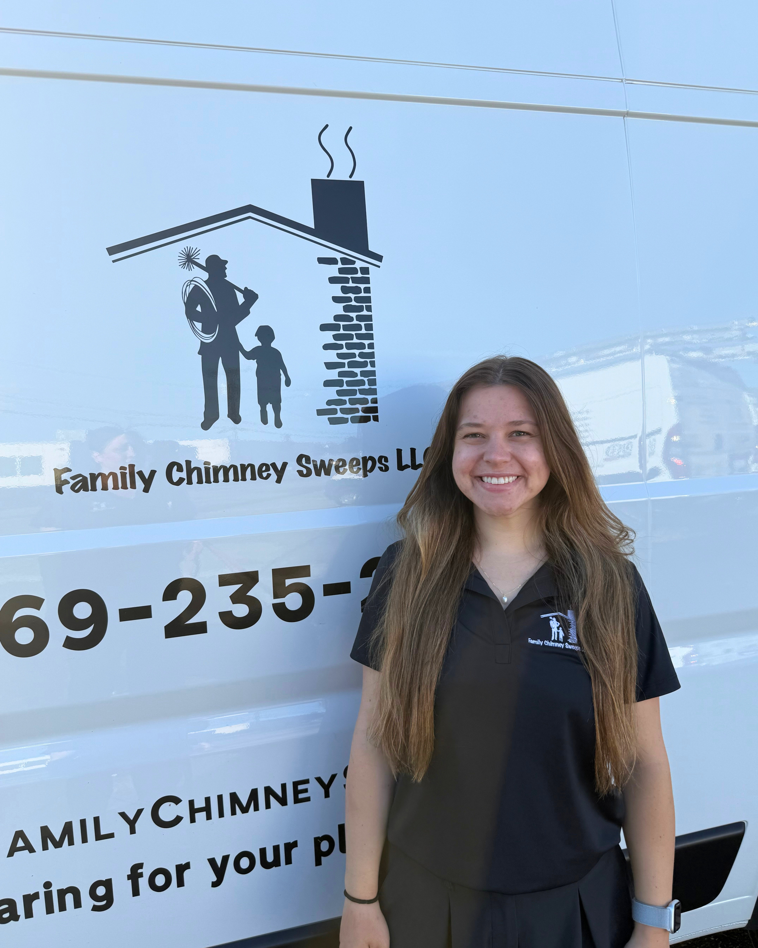 Young woman with long, wavy brown hair smiling in front of a white vehicle with a logo for Family Chimney Sweeps LLC.