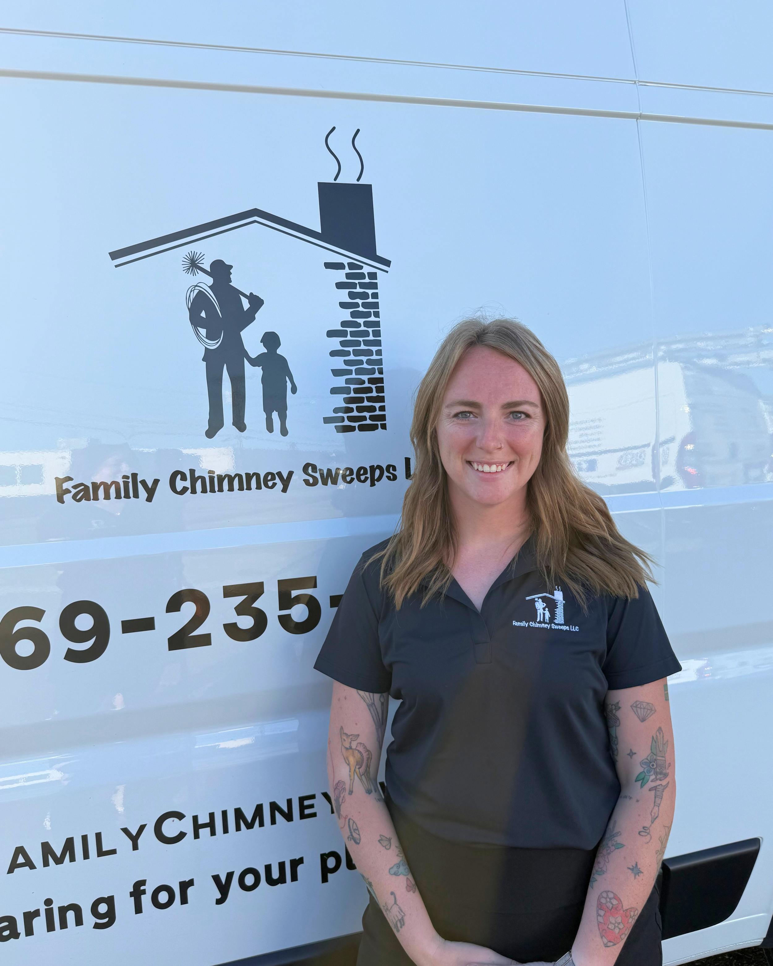 A young woman with long blonde hair smiling outside, wearing a navy blue polo shirt with the logo of Family Chimney Sweeps LLC. Behind her is a white van with the company logo and contact information.