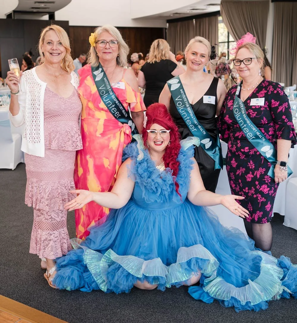 Famous Sharron seated on the floor in a frilly blue gown with 4 other ladies at a Melbourne Cup charity lunch..jpg