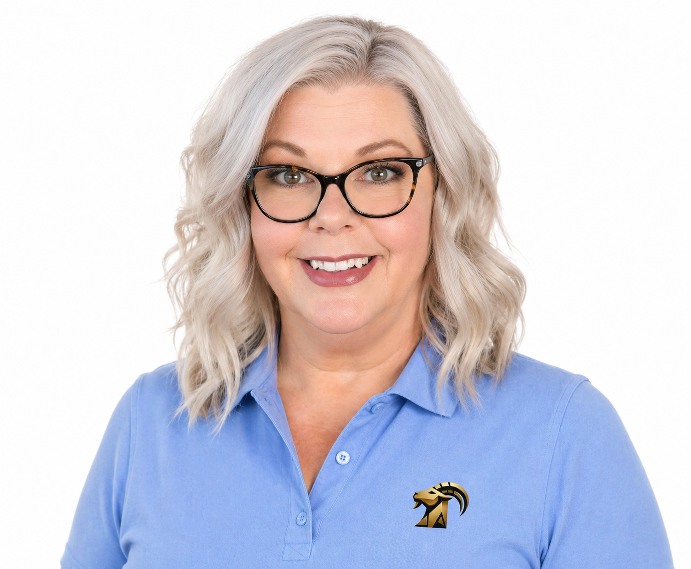 A woman with wavy, gray hair wearing glasses and a black shirt, smiling indoors with large windows in the background.