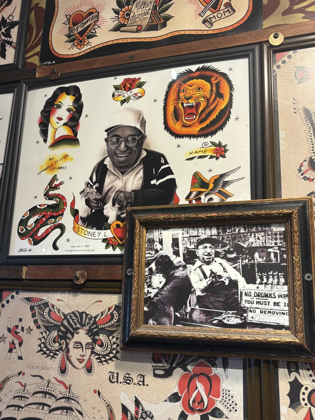 Stoney St. Clair tribute flash sheet and a framed photo of Stoney hanging among other flash sheets on the wall at Electric Street Tattoo, Oakland Park