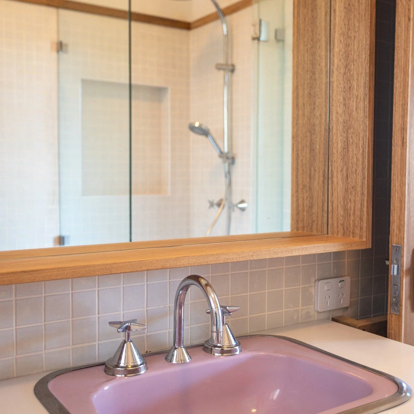 Pink basin. Enough said. This is not your average bathroom. 
This bathroom in our Thirroul renovation leans into retro tones while keeping the detailing sharp and contemporary. The colour pairing feels bold, but when grounded with warm timber and cle