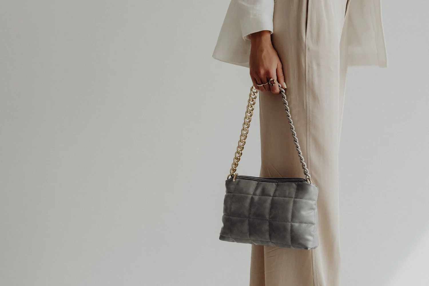 Female small business owner wearing cream linen holding a gray leather purse.
