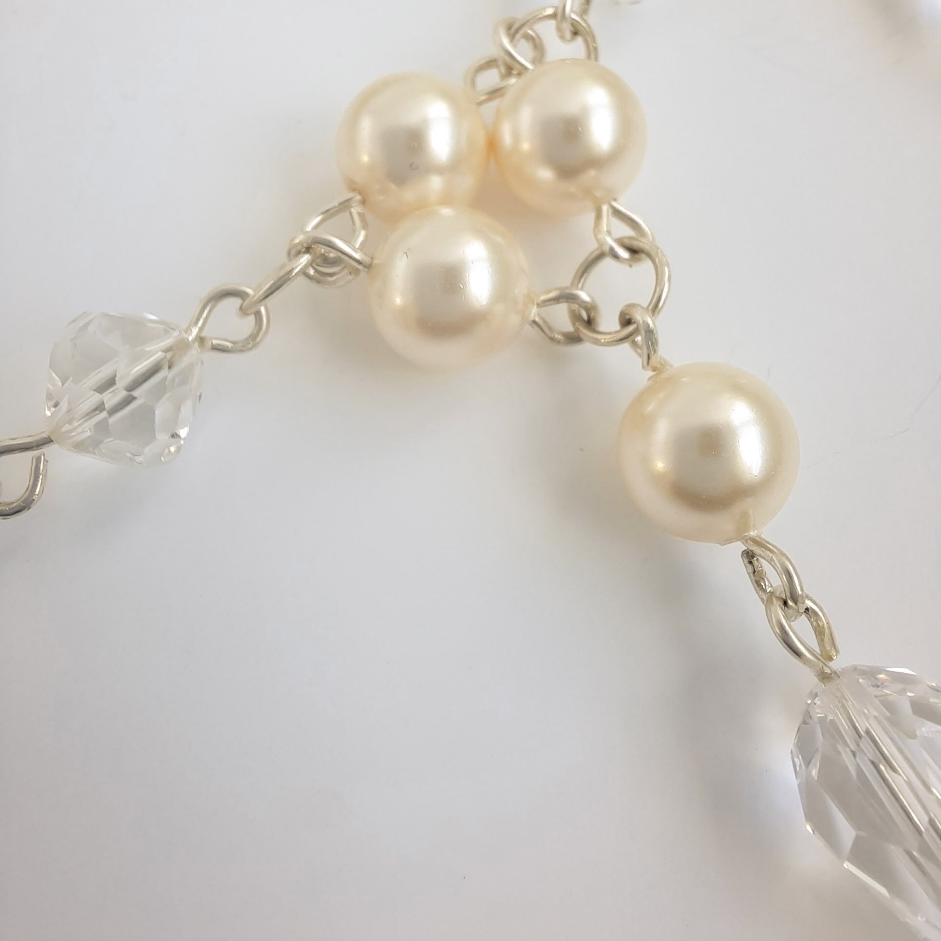 A Watermeadow Lane sterling silver statement necklace with five clusters of simulated pearls around the neck with each cluster droping down to have a number of crystals and pearls falling from it
