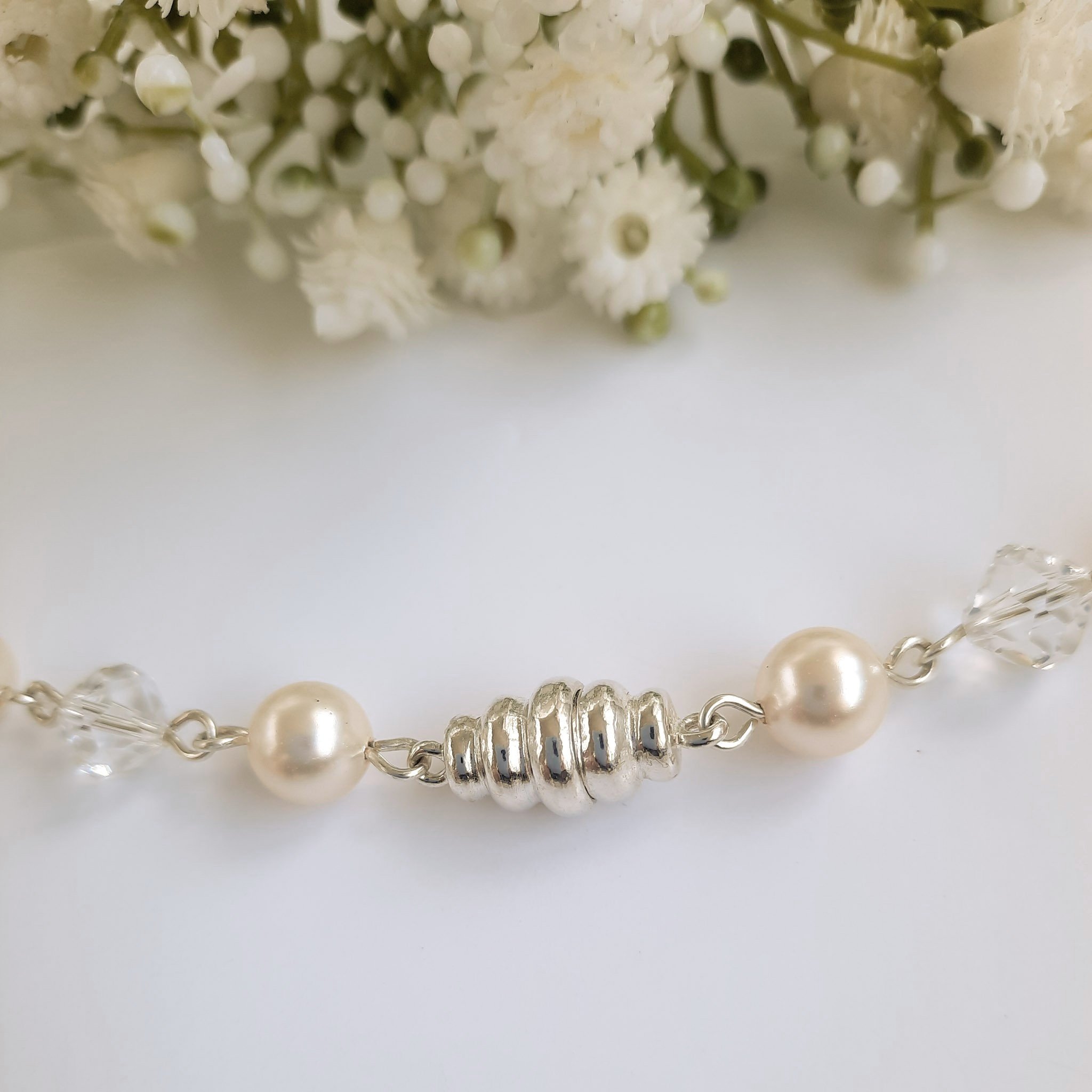 A Watermeadow Lane sterling silver statement necklace with five clusters of simulated pearls around the neck with each cluster droping down to have a number of crystals and pearls falling from it