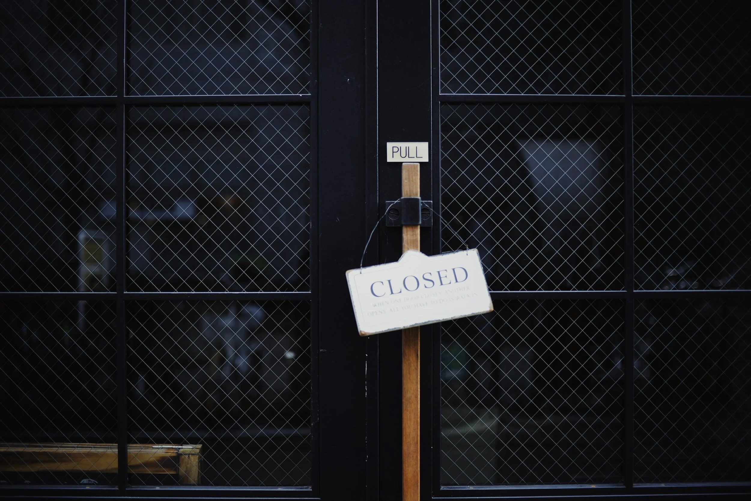 Glass door with wire mesh, "Closed" sign hanging, "Pull" label above handle.