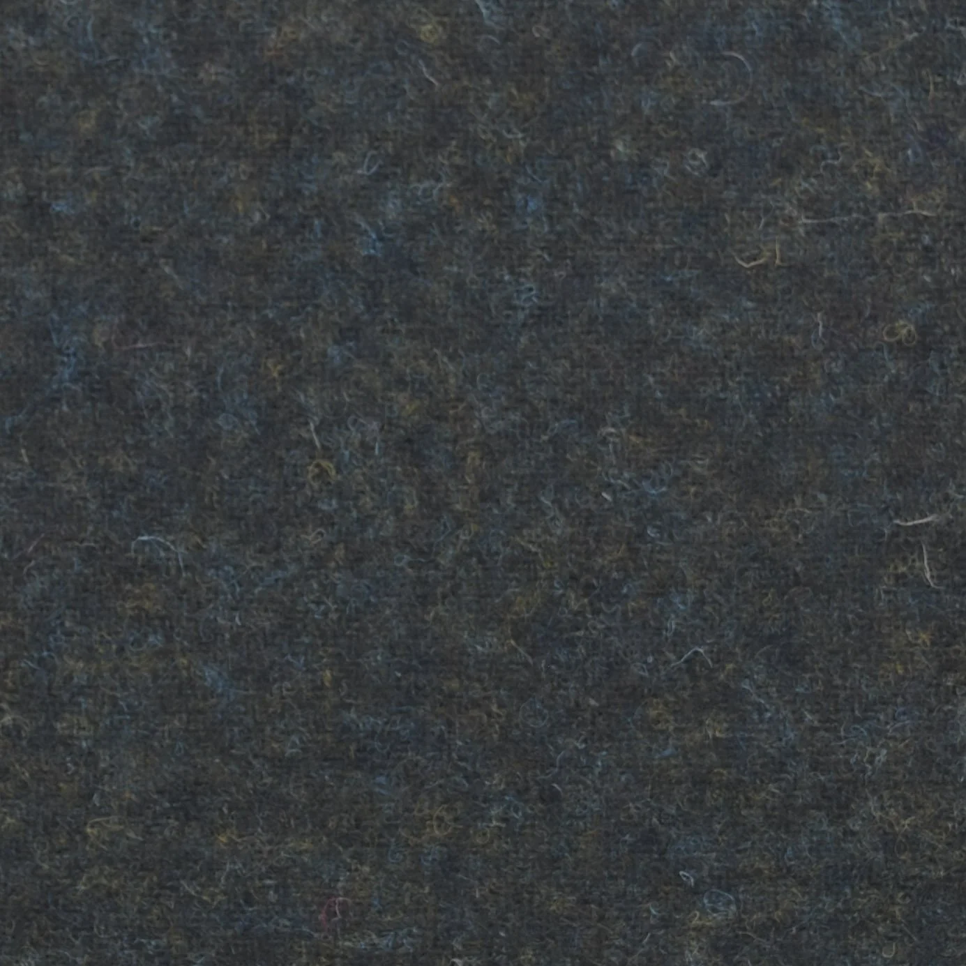 Close-up of a dark, textured surface, possibly fabric or felt, with various small fibers and subtle color variations.