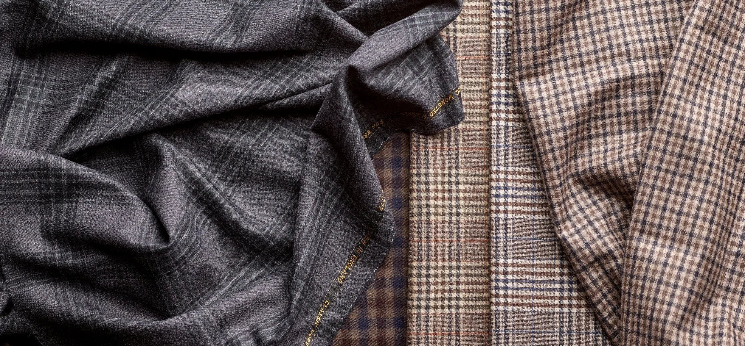 Five folded plaid fabric swatches in various shades of brown and gray, arranged side by side.