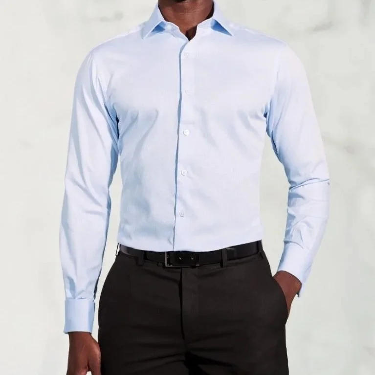 A man wearing a light blue button-up shirt and dark gray dress pants.