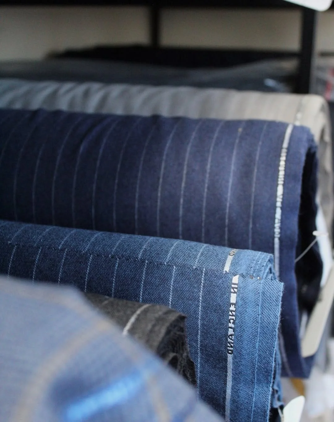 Stacked rolled fabric or clothing in various shades of blue and gray.