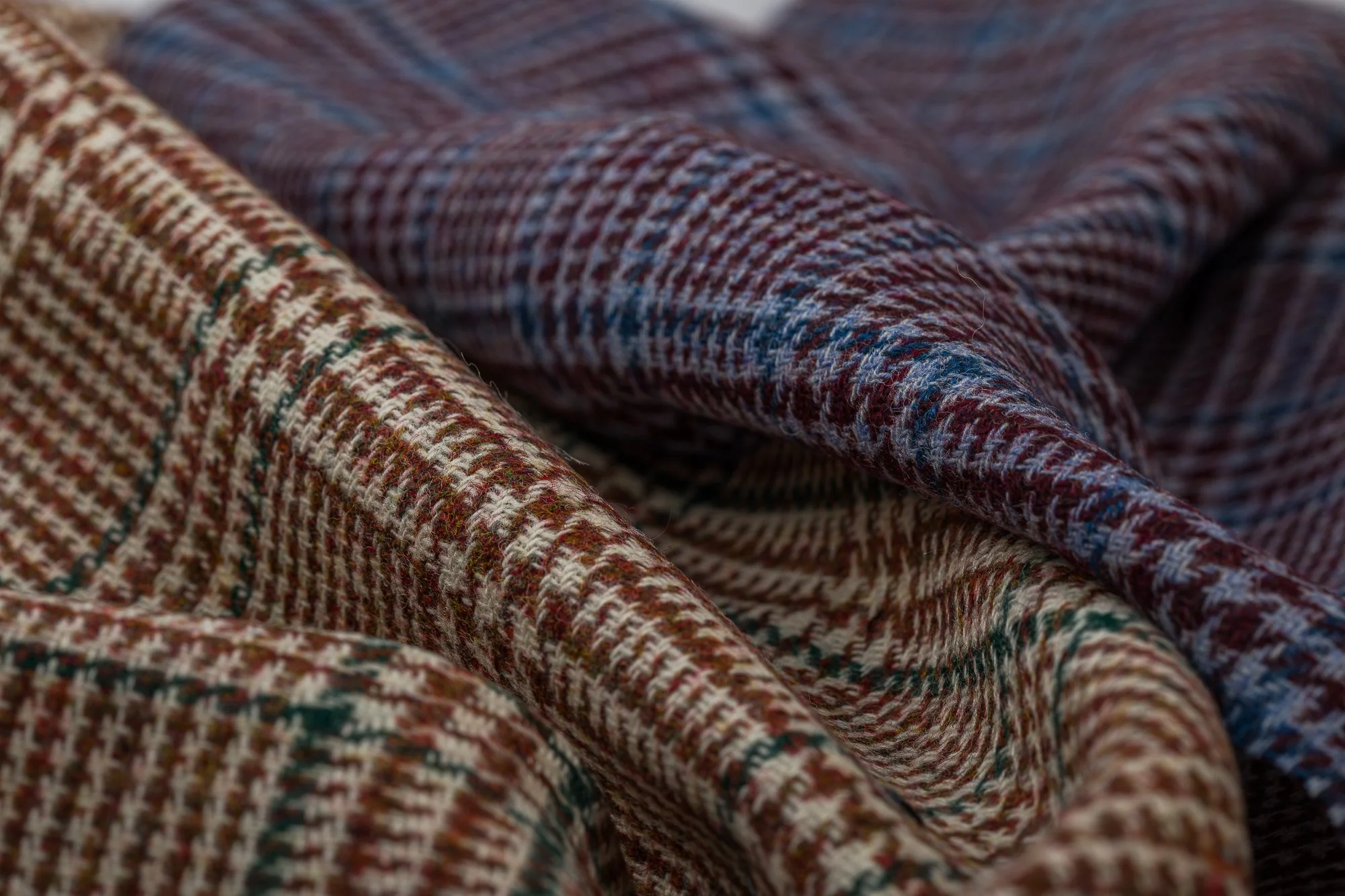 Close-up of folded plaid fabric with red, beige, blue, and green checkered pattern.