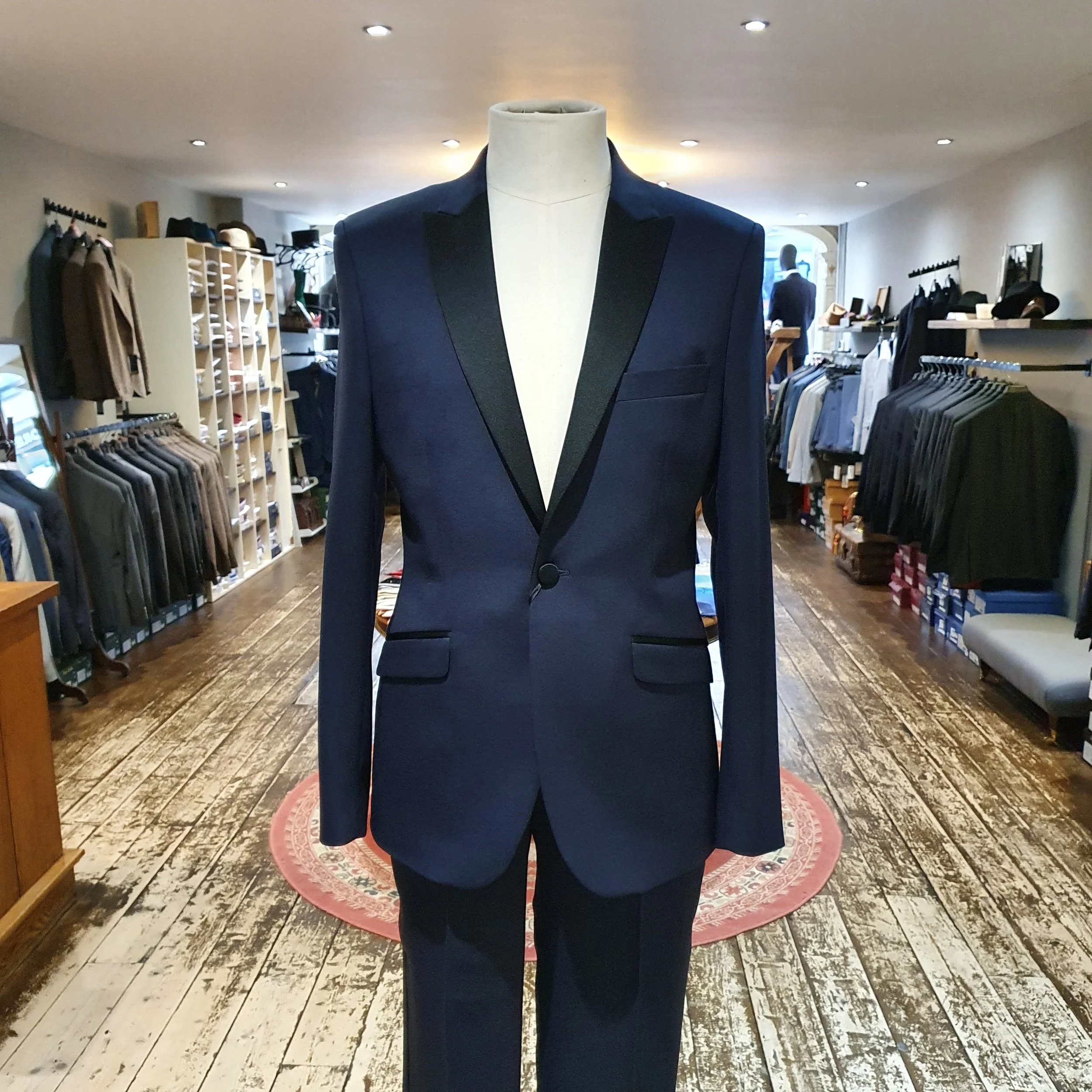 Blue tuxedo suit with black lapel on a mannequin inside a clothing store.