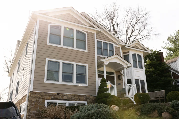 Custom home renovation by Omar Construction in Passaic County, NJ — tan siding craftsman-style residence with stone foundation