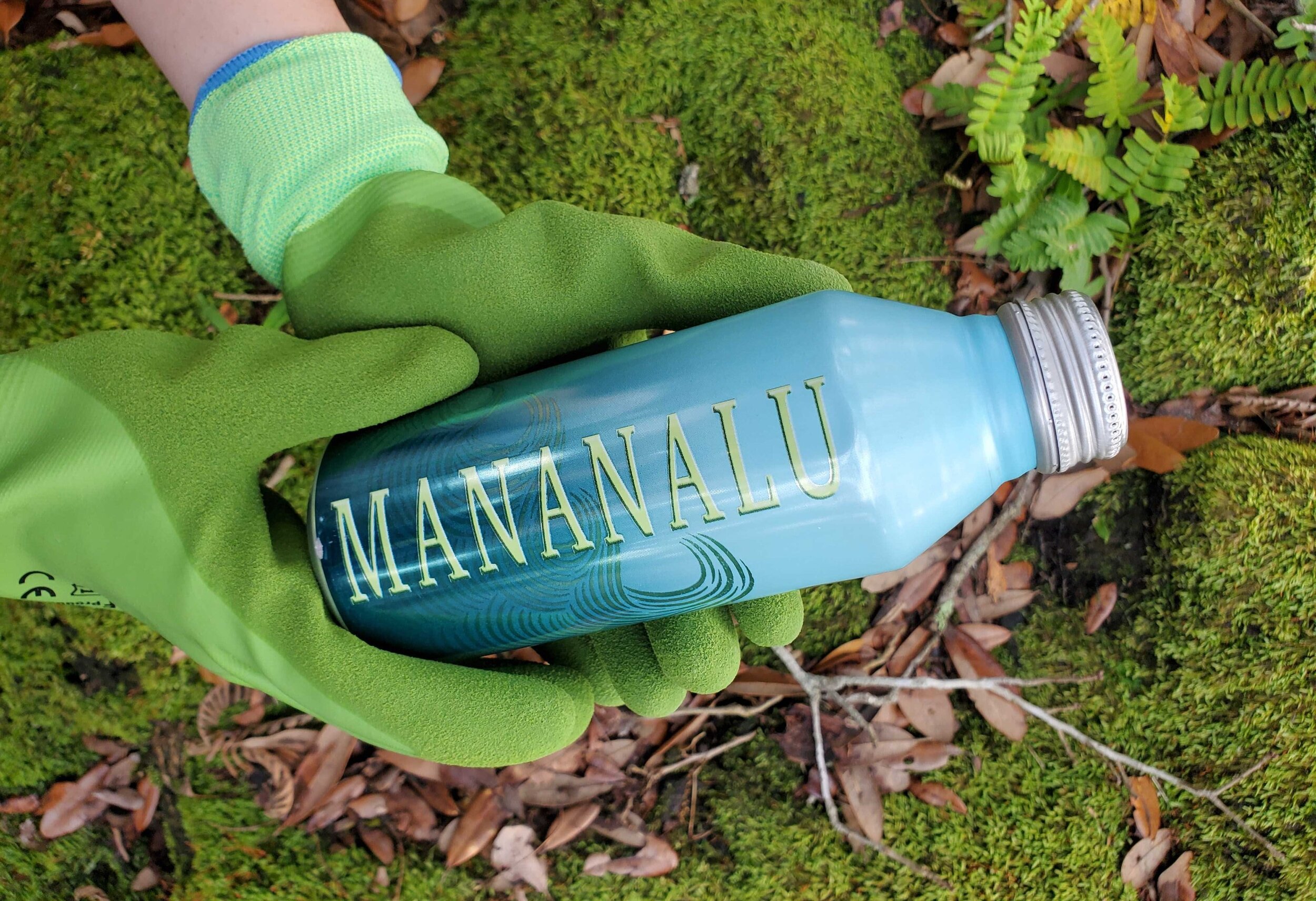 Green gloves holding a Mananalu aluminum water bottle.
