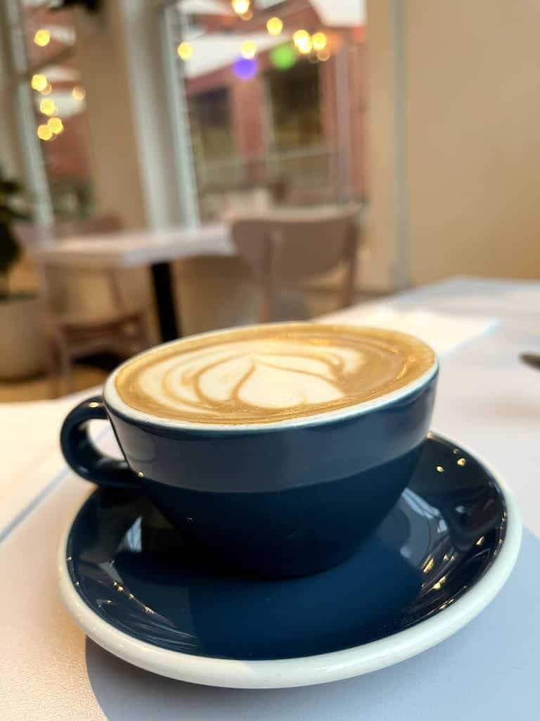  Cappuccino servido em xícara e pires na cor azul e com bordas brancas 