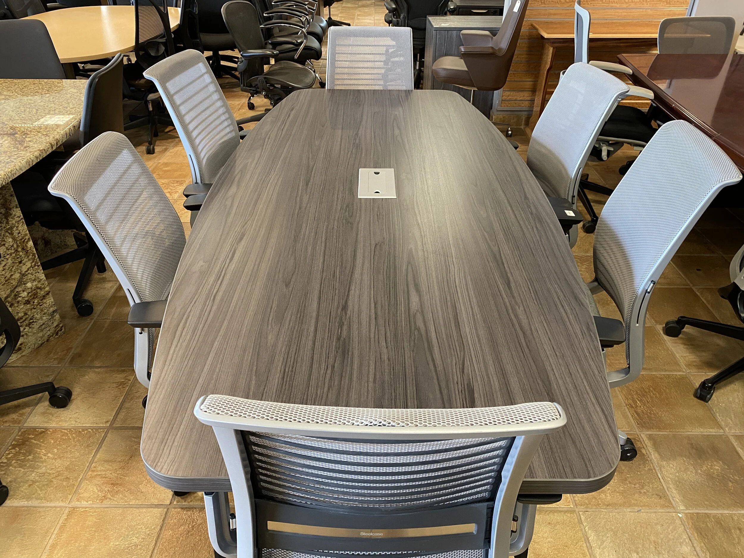 A conference room table with eight mesh-backed chairs around it.