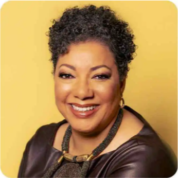 Portrait of a woman with short curly gray hair, smiling, wearing a black top and a necklace against a yellow background.
