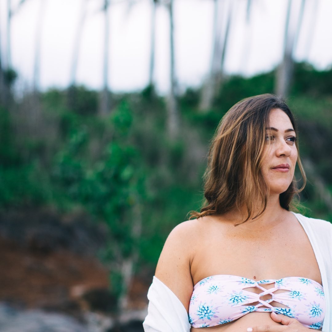Woman in floral bikini top standing outdoors with blurred green background