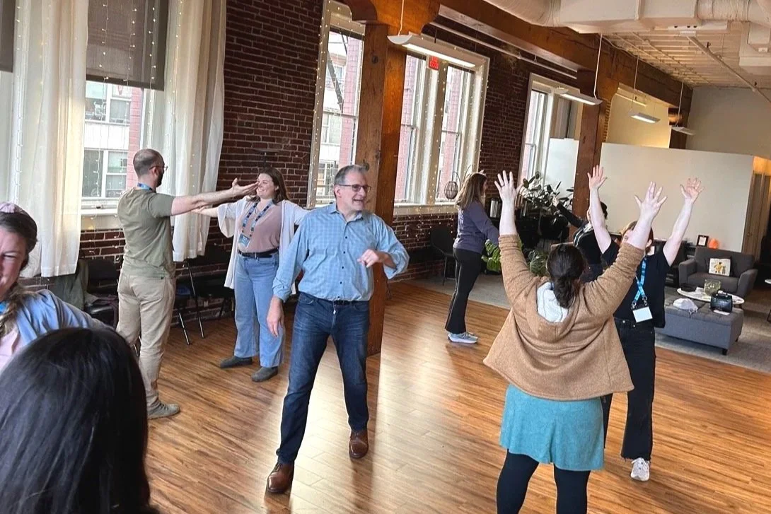 Members of a young professionals organization shown here, standing in pairs, and working with David during an improv game that requires mirroring one another.