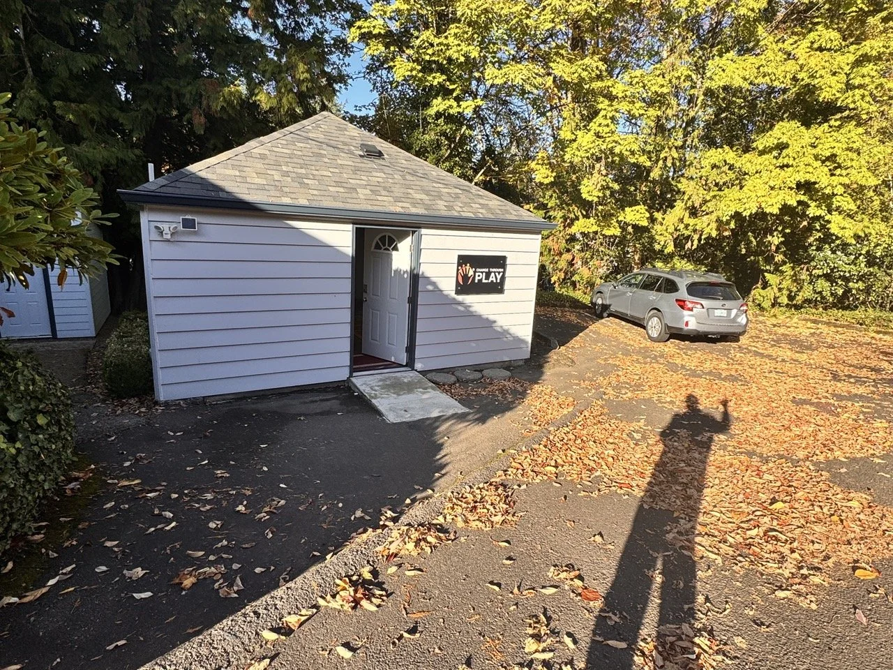 A sunny day in autumn with leaves all over the ground in front of our studio. There's a long shadow of the person taking the photo just before an improv class.