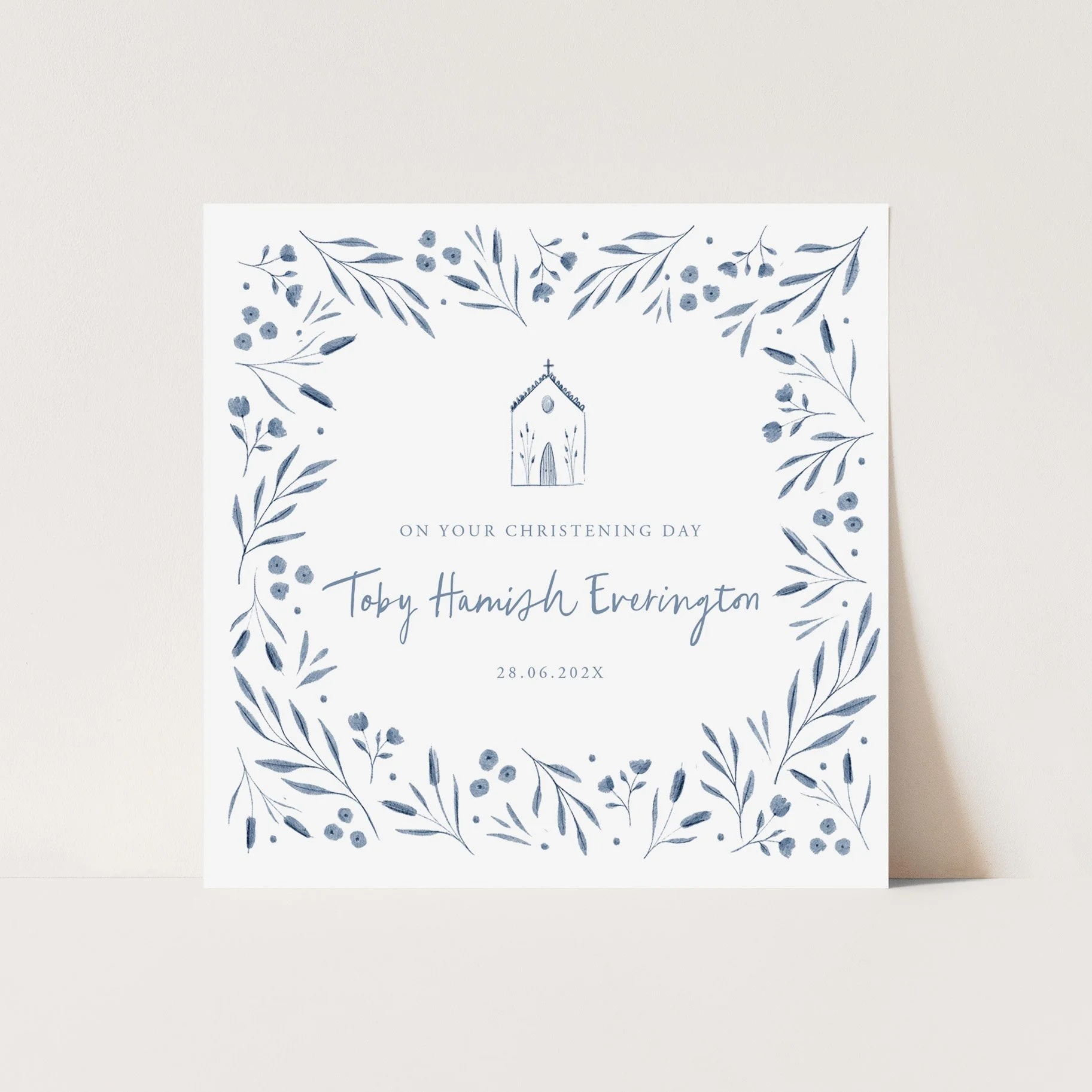 A white card with blue floral illustrations and a church drawing in the center, with the text 'On Your Christening Day' personalised with a name and date written below.