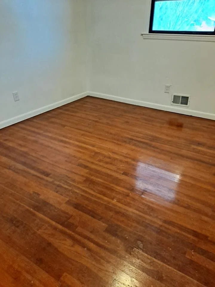 Empty room with hardwood floors, white walls, a window, and an air vent.