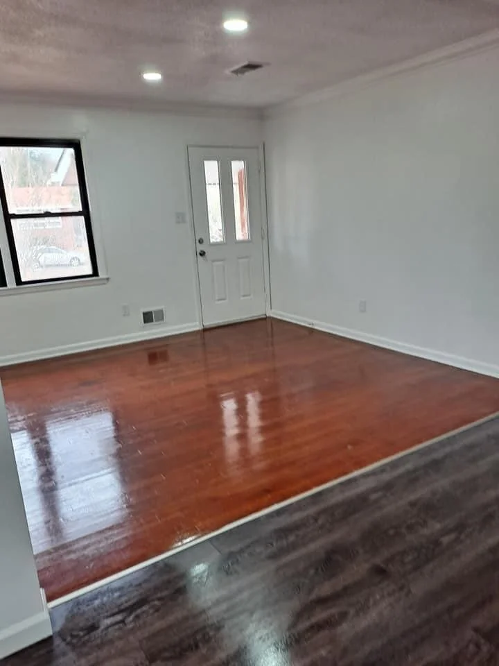 Empty room with white walls, hardwood floors, a window, and a door.