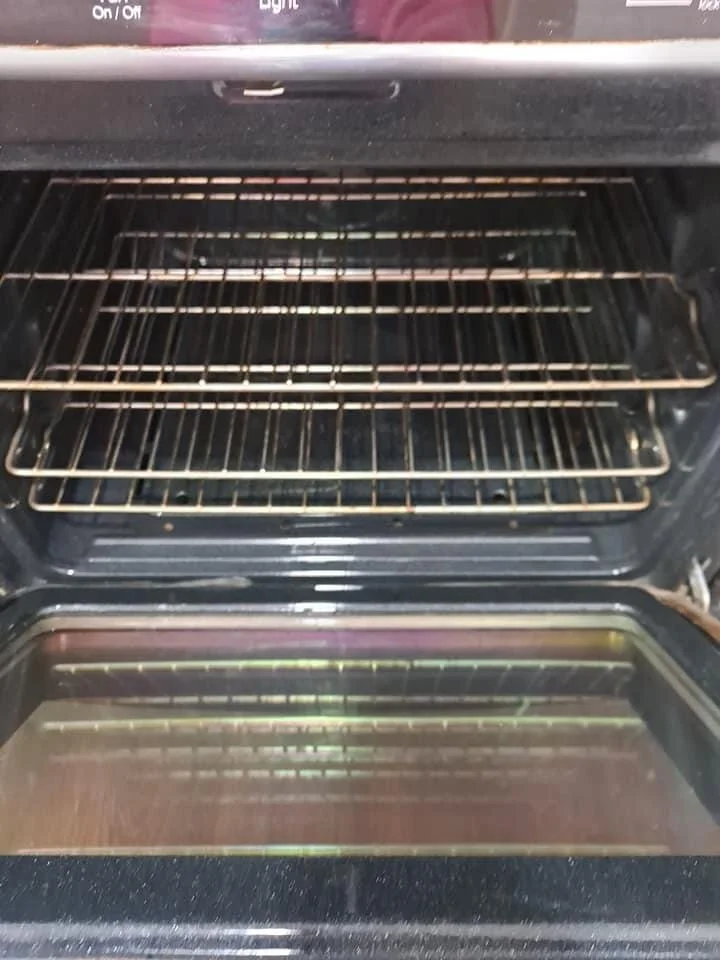 Inside view of an empty oven with racks and an oven door with a glass window.