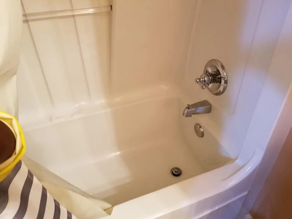 Empty white bathtub with a faucet, a drain, and a wall-mounted shower control.